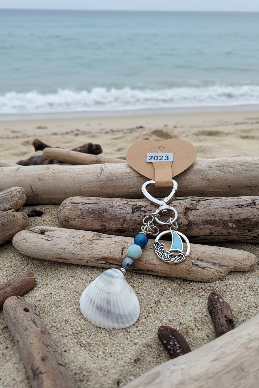 Coastal sailboat scallop shell bag charm close-up on white leather bag