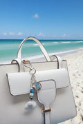 Coastal sailboat scallop shell bag charm on white bag showing sailboat charm detail