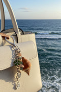 Florida conch shell Laugh bag charm close-up on white leather bag