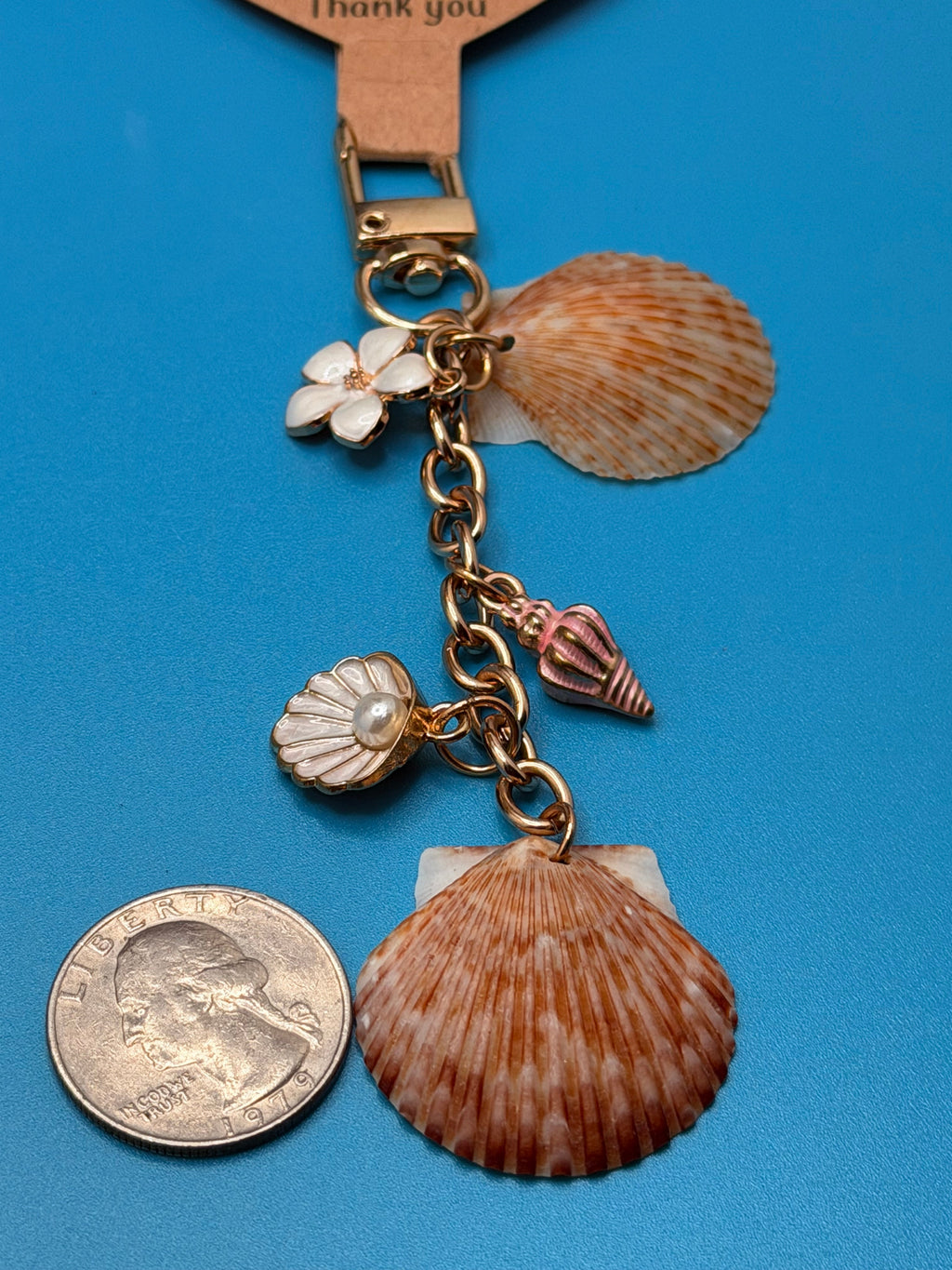 Chocolate seashell bag charm clipped to woven straw bag