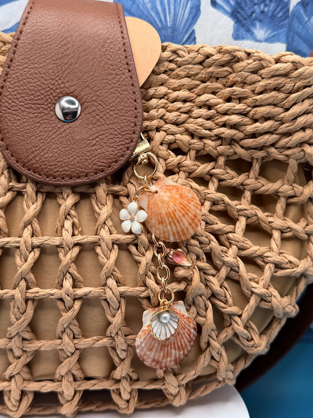 Chocolate seashell bag charm on woven straw bag showing full charm length
