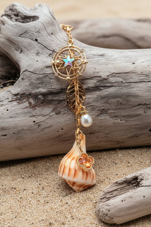 Celestial Shores lightning whelk shell bag charm styled on woven straw bag showing compass star charm