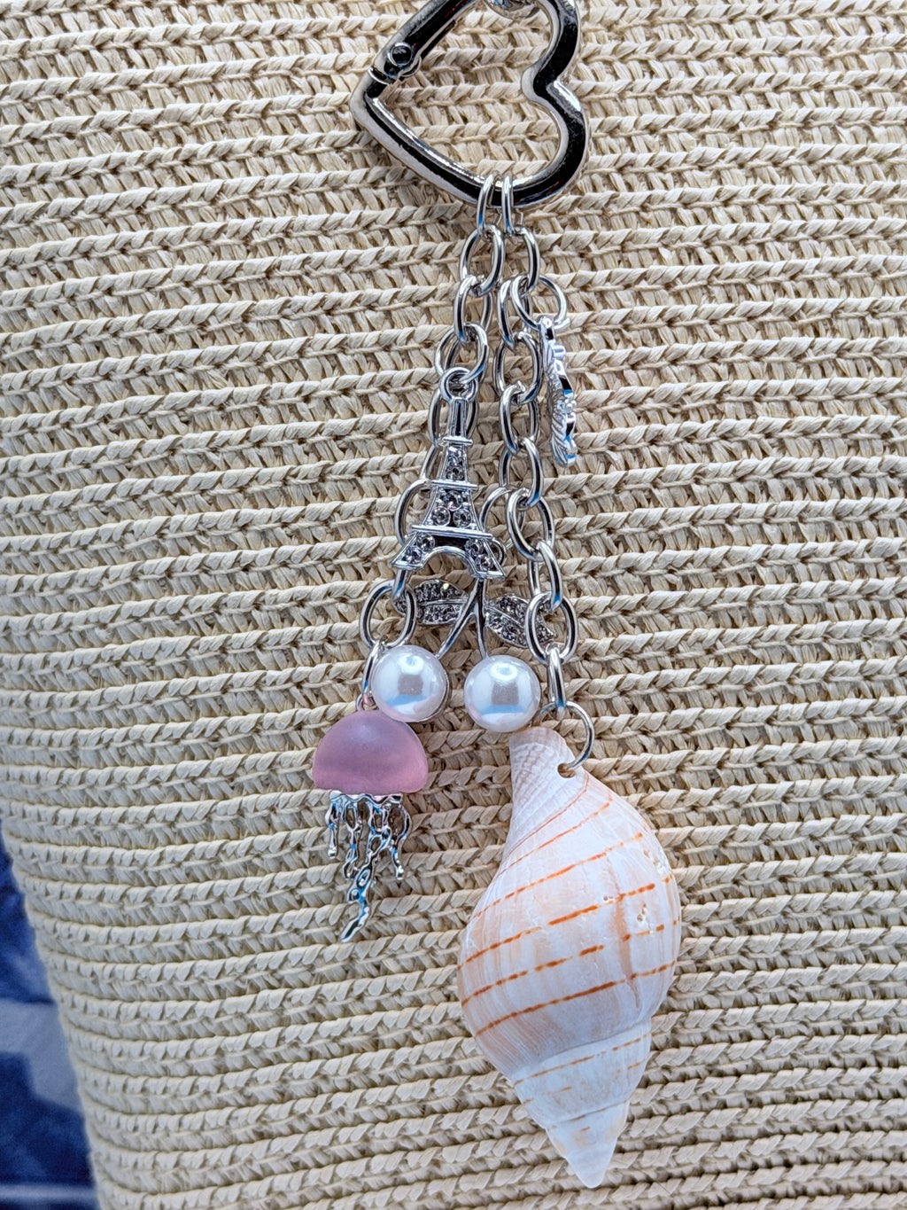 Coastal charm shell keychain displayed on a woven straw bag