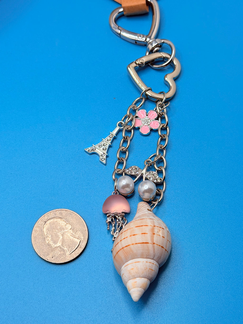 Coastal charm shell keychain shown next to a quarter for size reference