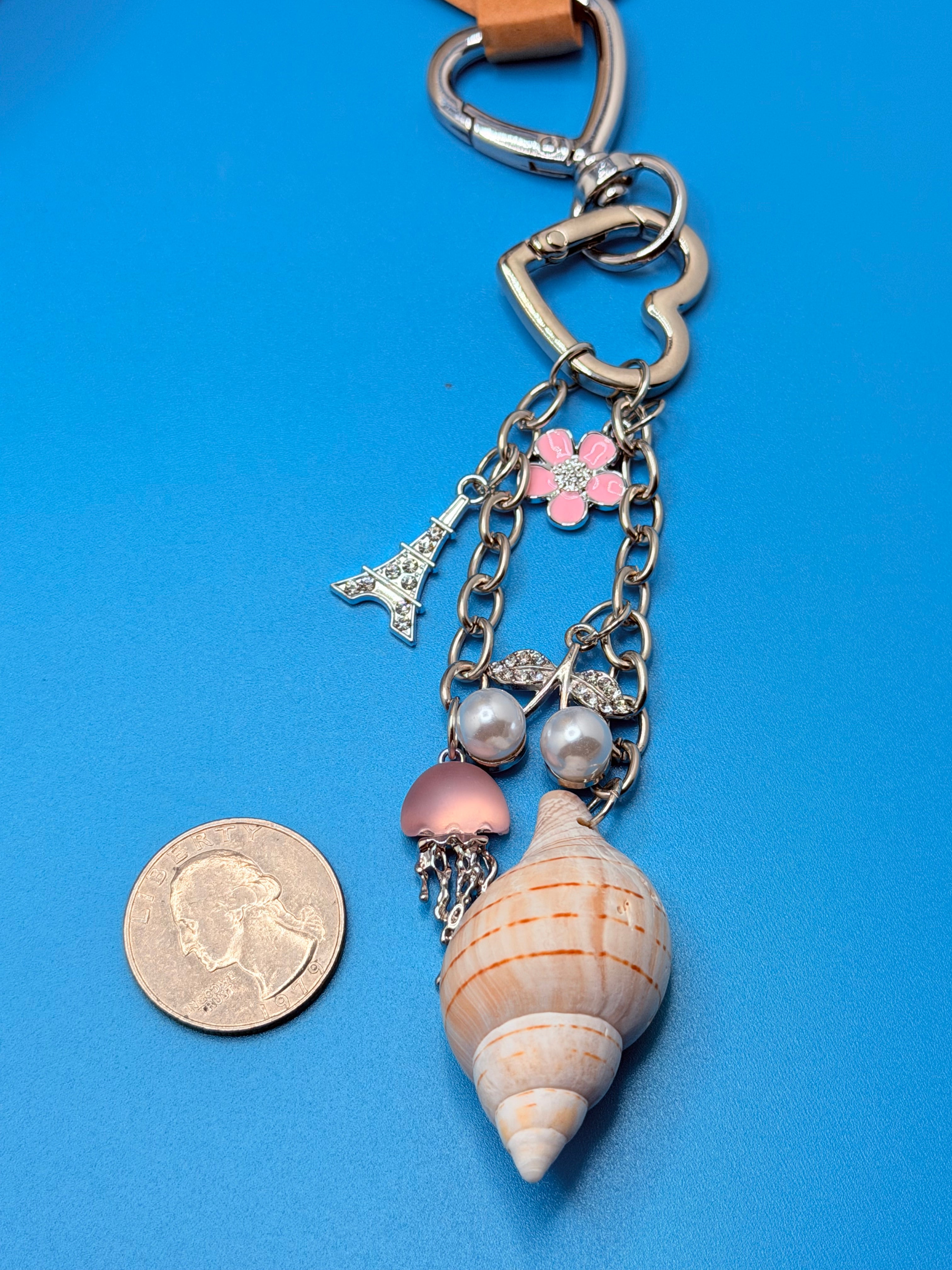 Coastal charm shell keychain shown next to a quarter for size reference
