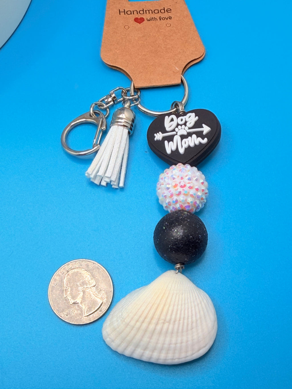 Dog Mom ark shell keychain with quarter for scale on blue background showing Dog Mom heart charm