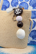 Dog Mom ark shell keychain on woven straw bag showing white tassel and lobster clasp