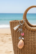 Believe and Bloom slipper shell keychain with quarter for scale on blue background showing crystal bow charm