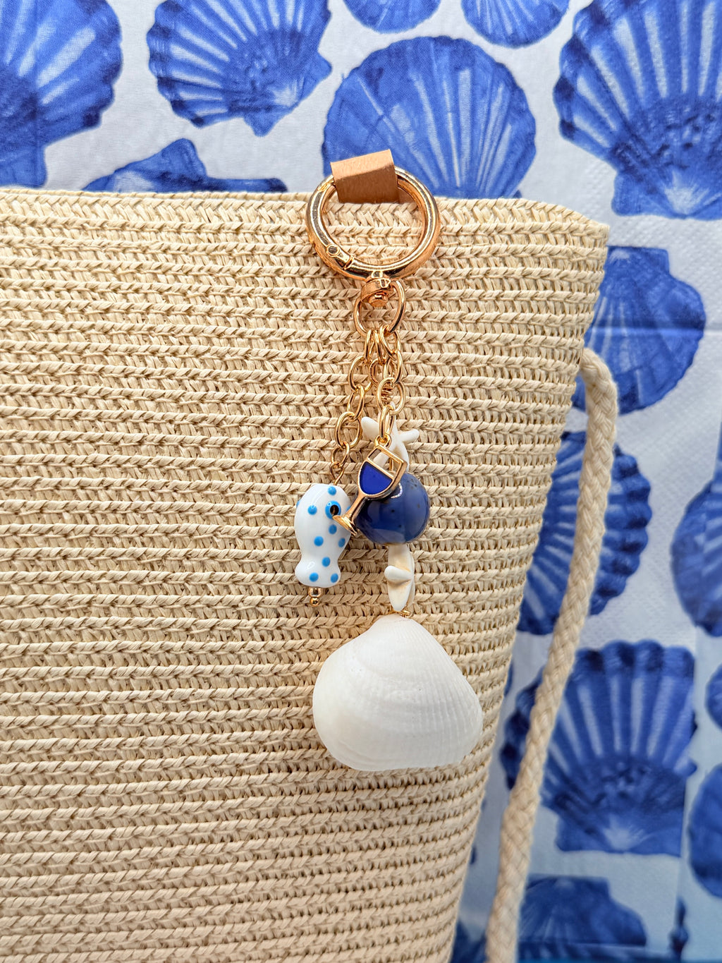 Florida ark shell bag charm on woven straw tote bag showing side angle with blue shell print background
