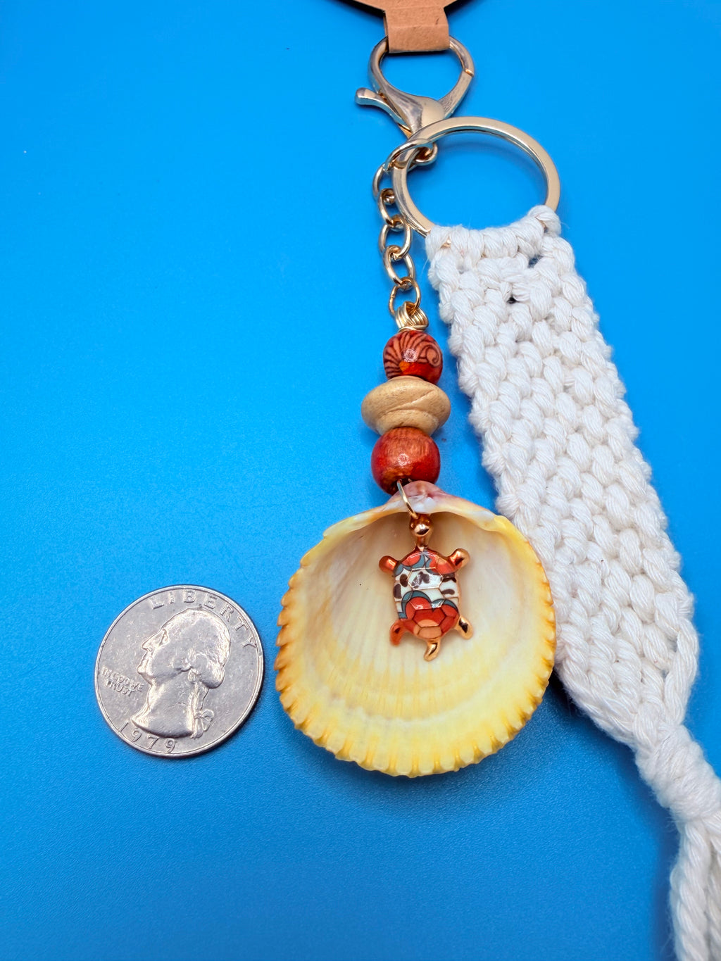 Turtle Cove prickly cockle shell macrame keychain close-up on woven straw bag showing sea turtle charm inside shell