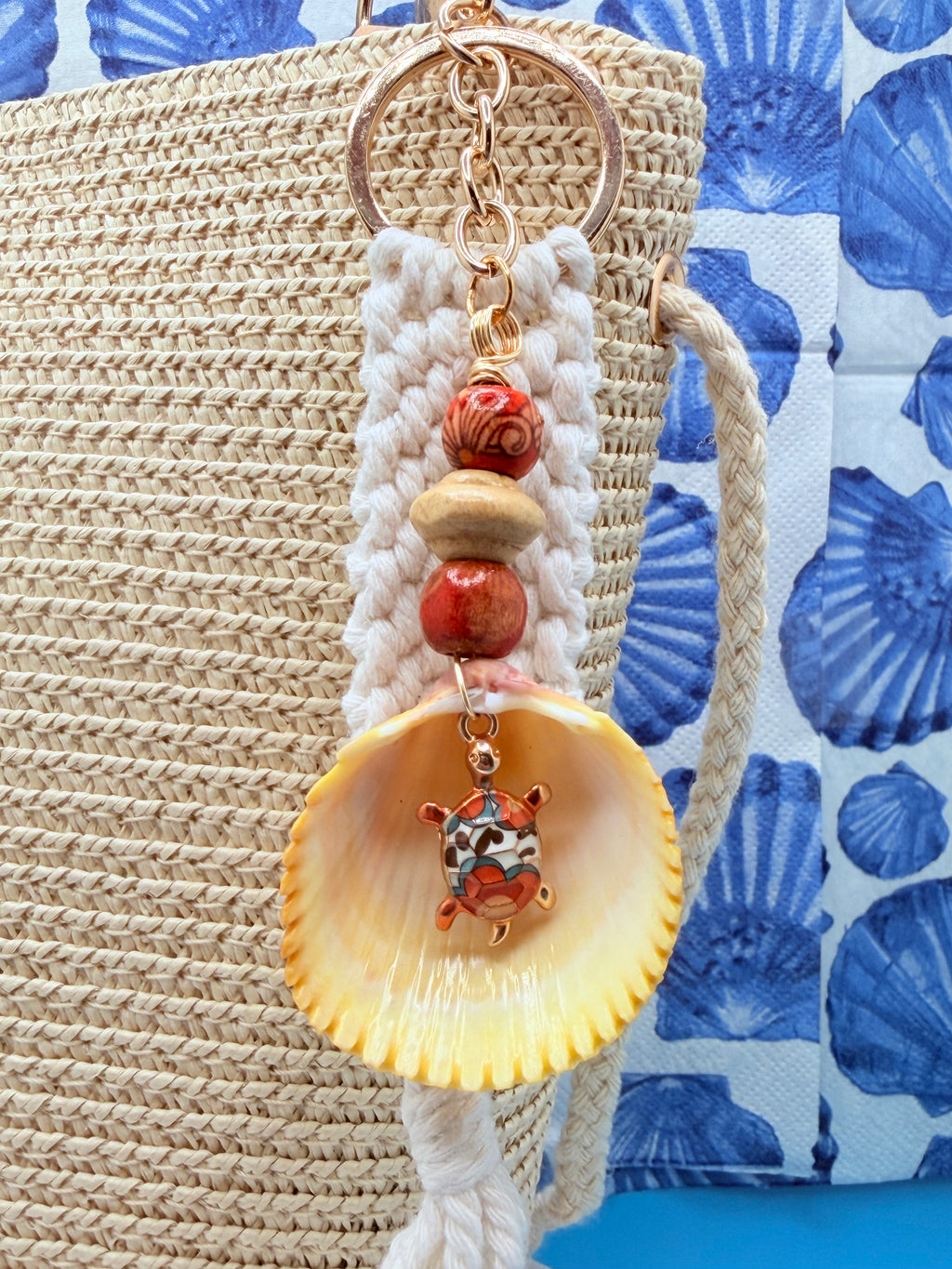 Turtle Cove prickly cockle shell macrame keychain with quarter for scale on blue background showing full length