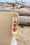 Turtle Cove prickly cockle shell macrame keychain on woven straw bag showing scallop shell and macrame tassel