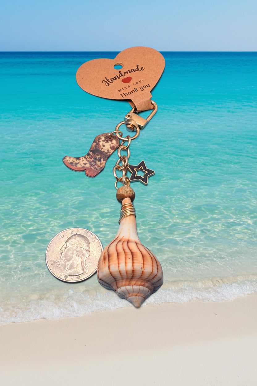 Boots and the Shore lightning whelk shell bag charm on white handbag with shell print background showing full styling