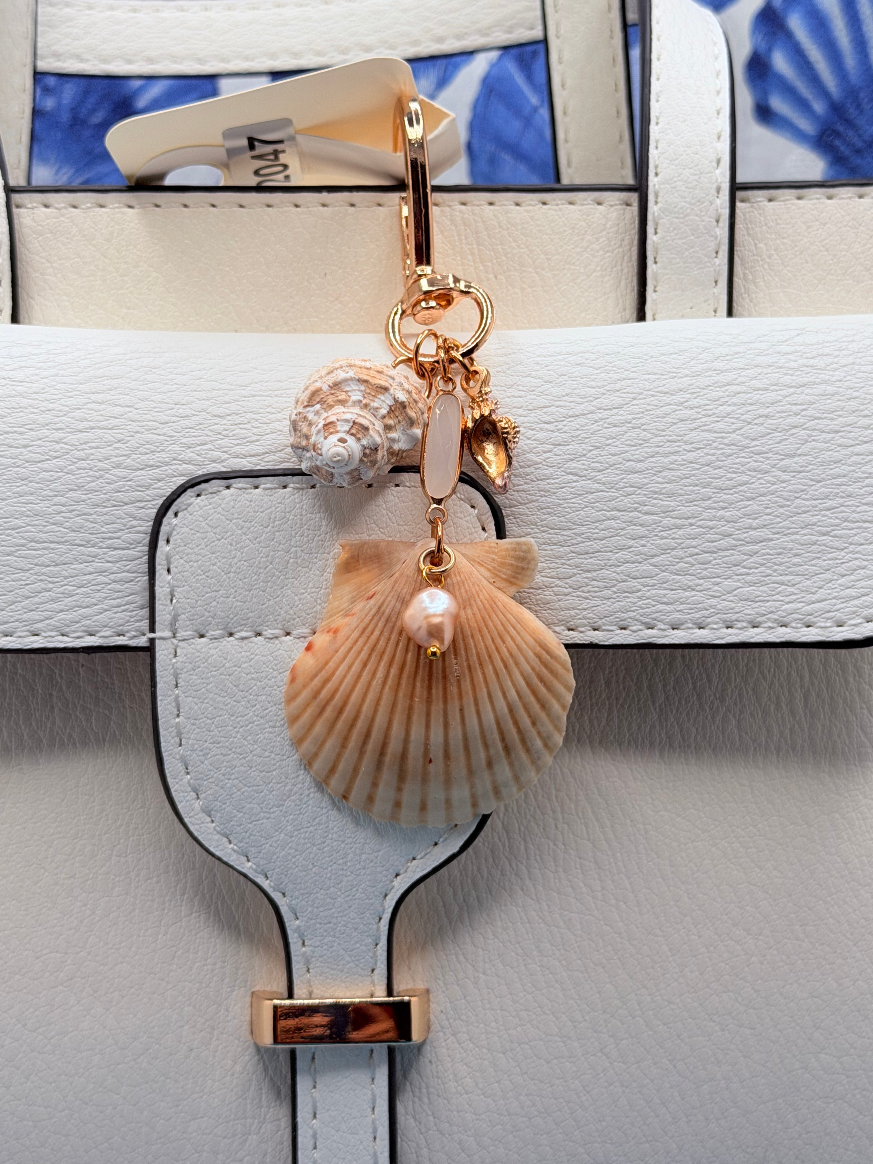 Dual Shores bag charm close-up on white leather bag showing scallop shell and pearl drop