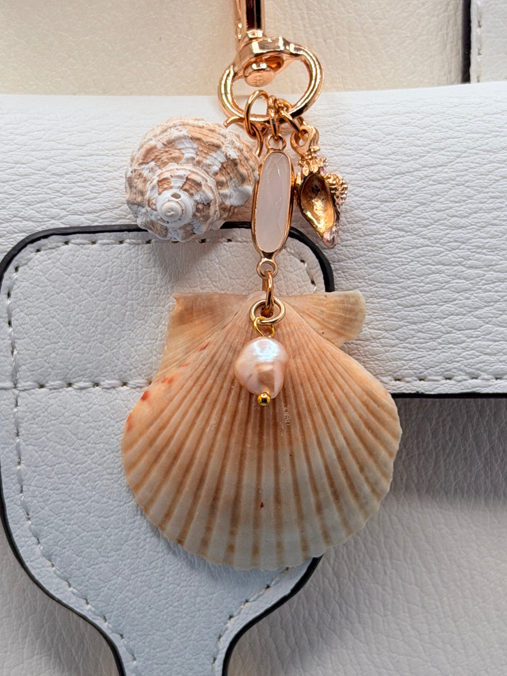 Dual Shores bag charm with scallop and turban shell on white structured handbag