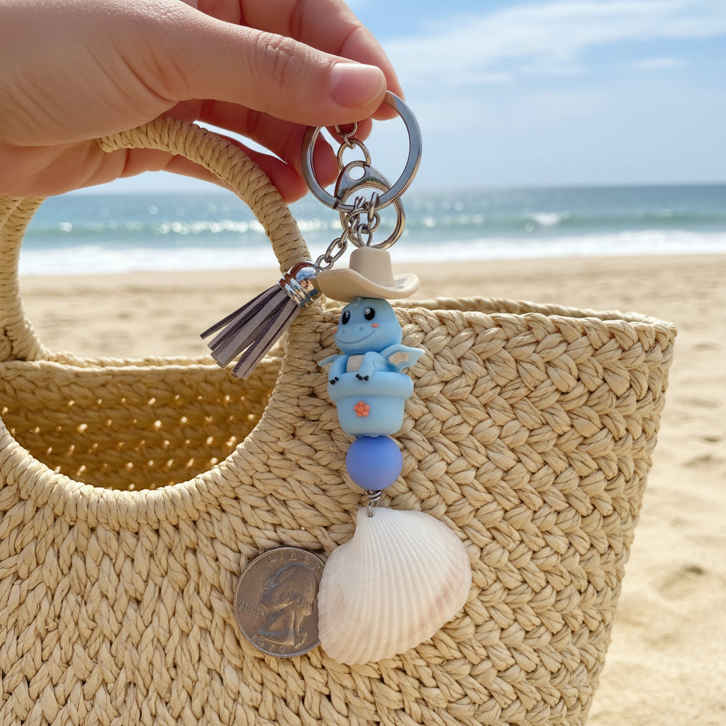 Cowboy Dragon ark shell keychain on white handbag showing ark shell at bottom with blue floral background