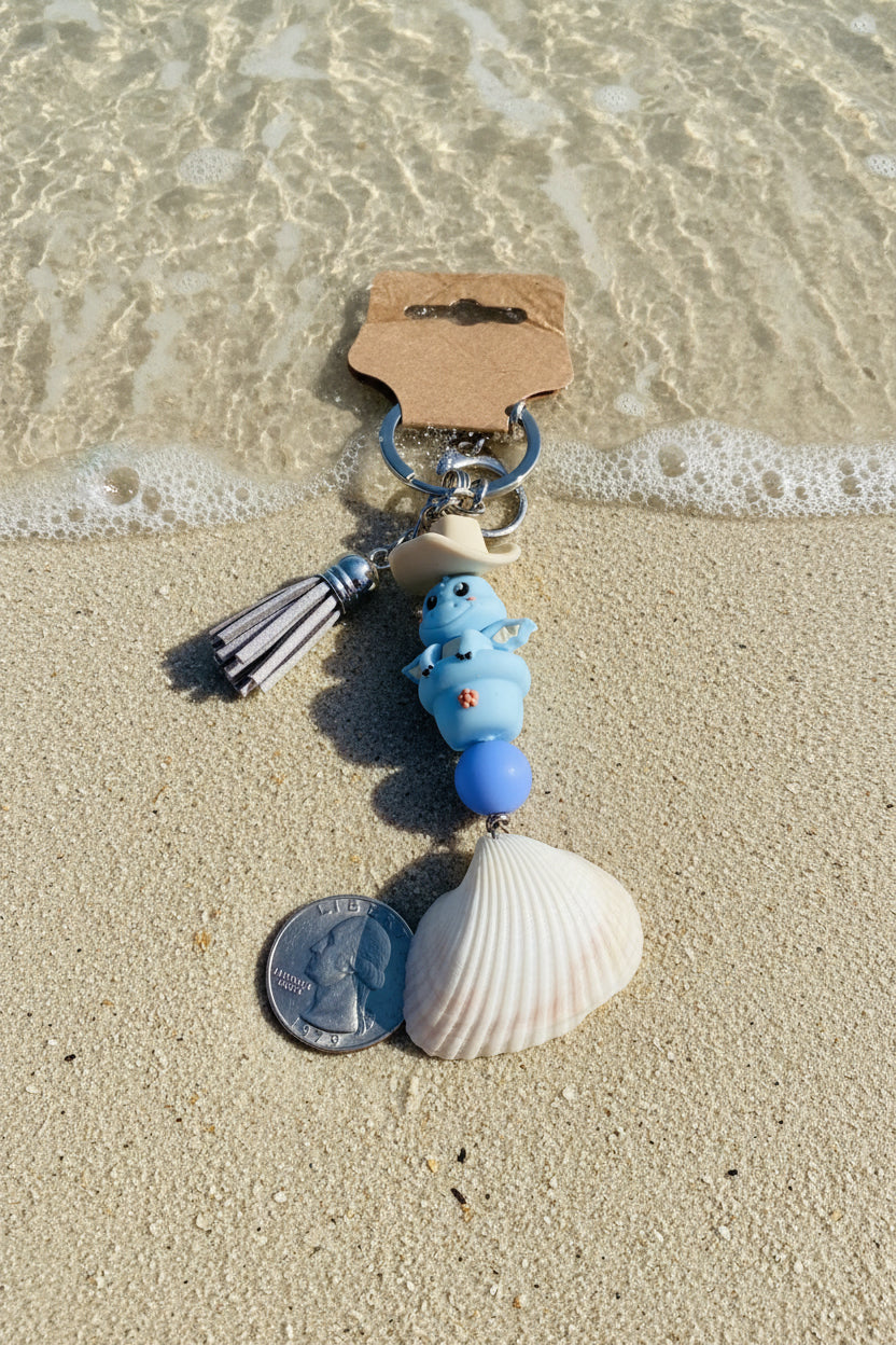 Cowboy Dragon ark shell keychain styled on white handbag with blue shell print background showing full keychain