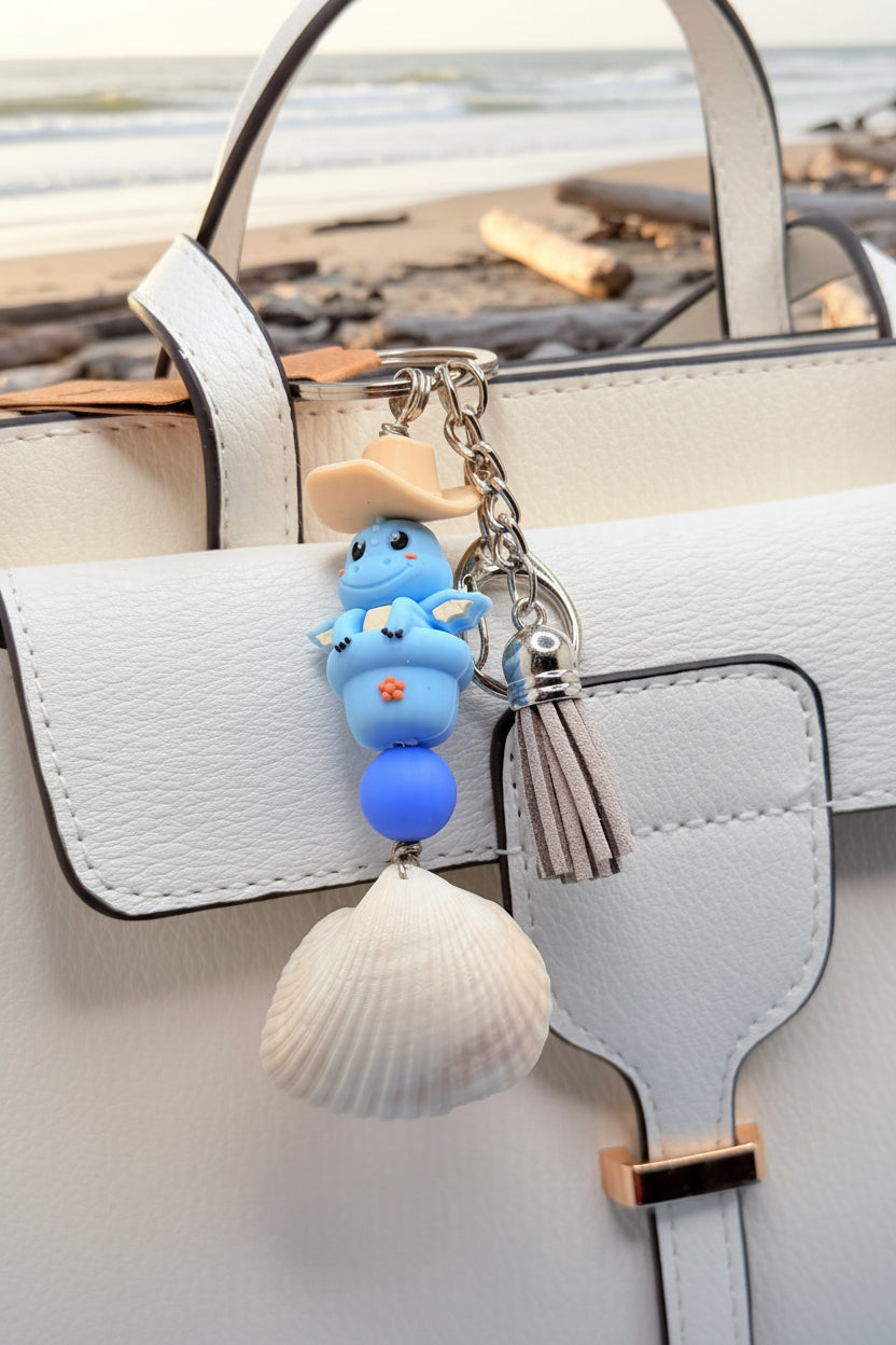 Cowboy Dragon ark shell keychain with quarter for scale on blue background showing dragon figure and tassel