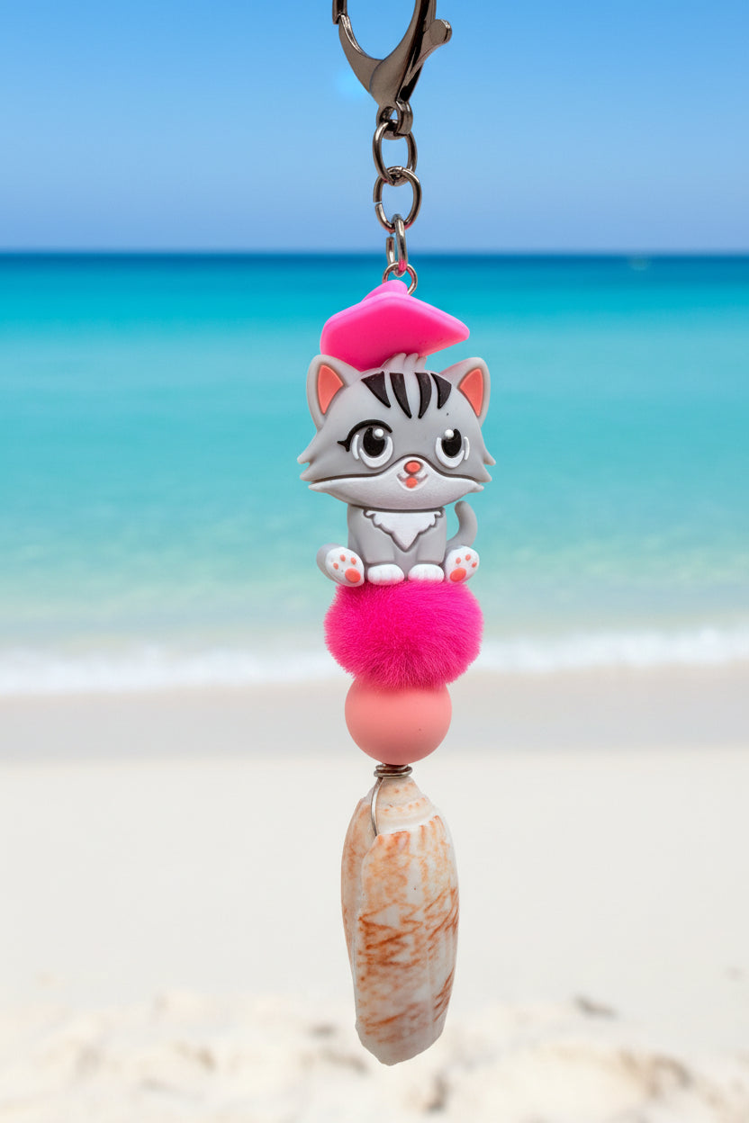 Pink Beret Cat lettered olive shell keychain on white handbag close-up showing grey tabby cat with hot pink beret