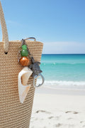 Sea Turtle conch shell bottle opener keychain styled on woven straw tote bag with blue shell print background