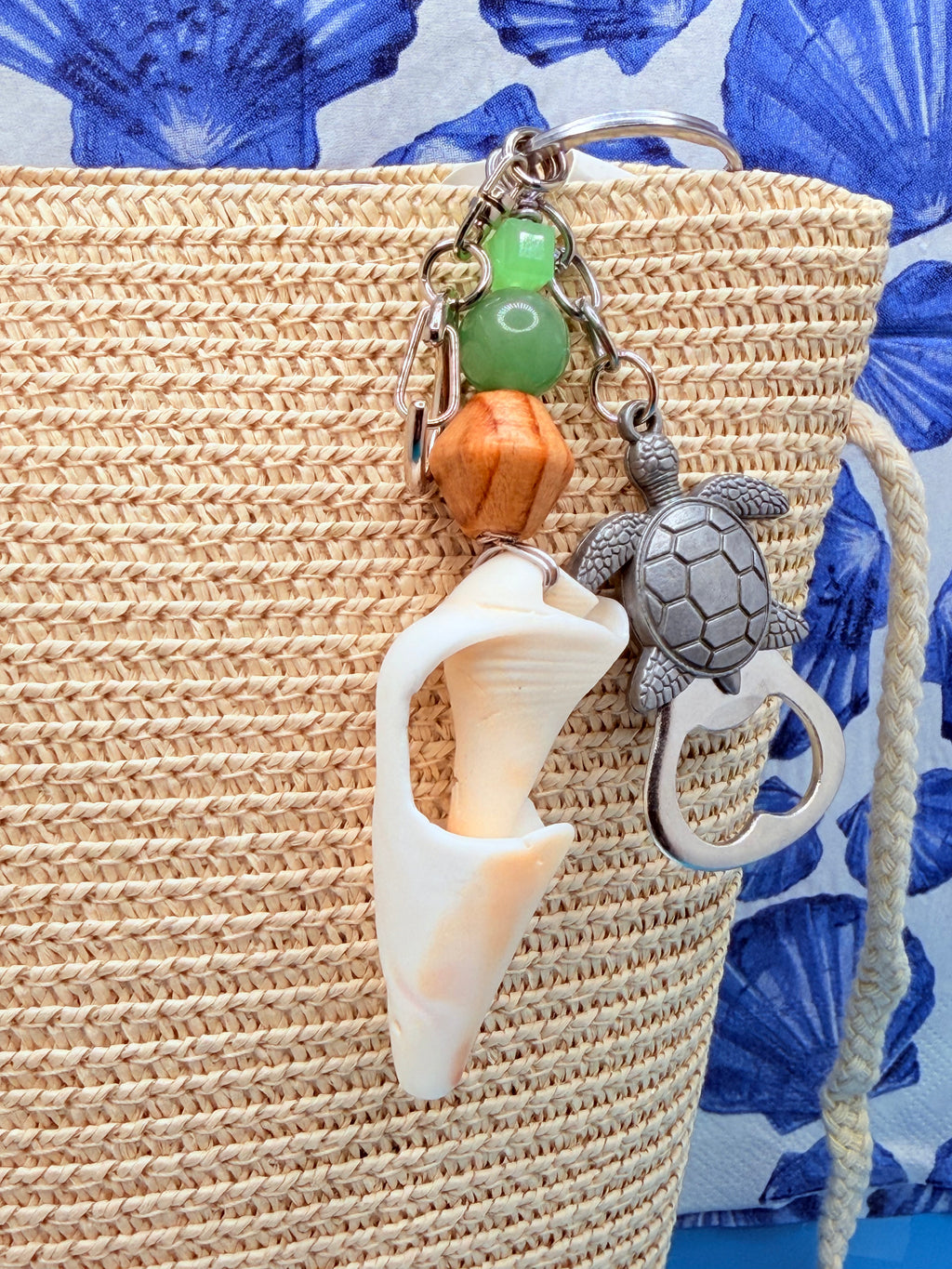 Sea Turtle conch shell bottle opener keychain on woven straw bag showing full charm cascade with turtle bottle opener