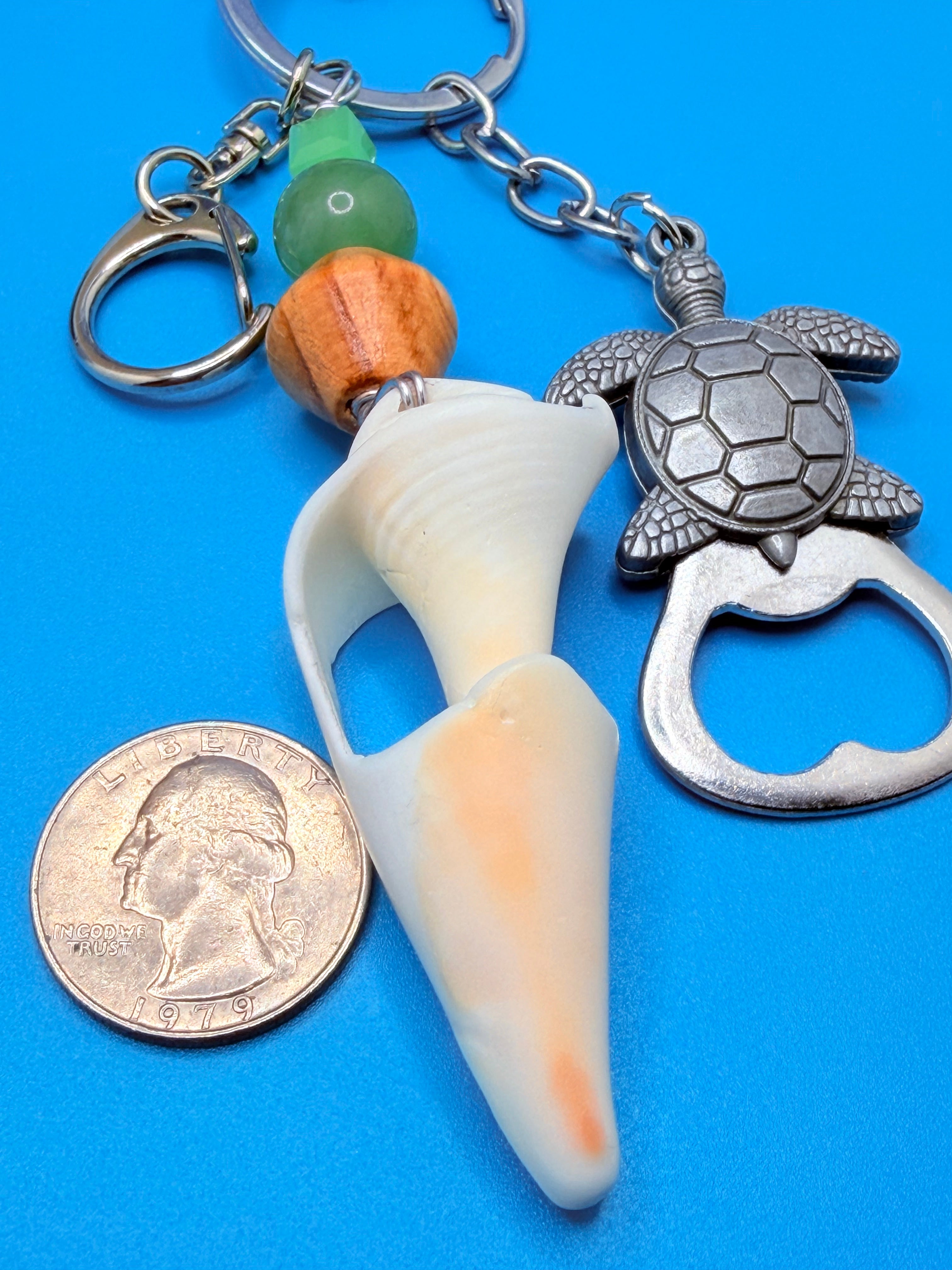 Sea Turtle conch shell bottle opener keychain with quarter for scale on blue background showing full keychain and SKU tag