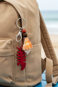 Florida conch shell red fishbone bottle opener keychain with quarter for scale on blue background showing conch shell close-up