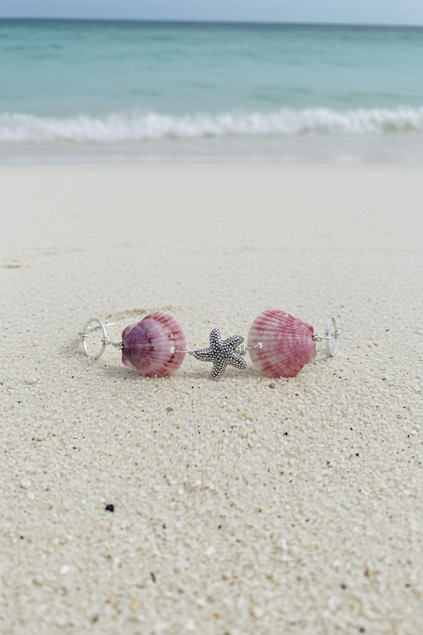 Purple calico scallop shell and starfish bracelet on burlap pillow with tag showing 7.5 adjust