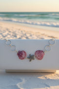 Purple calico scallop shell and starfish bracelet on white jewelry display stand showing full length
