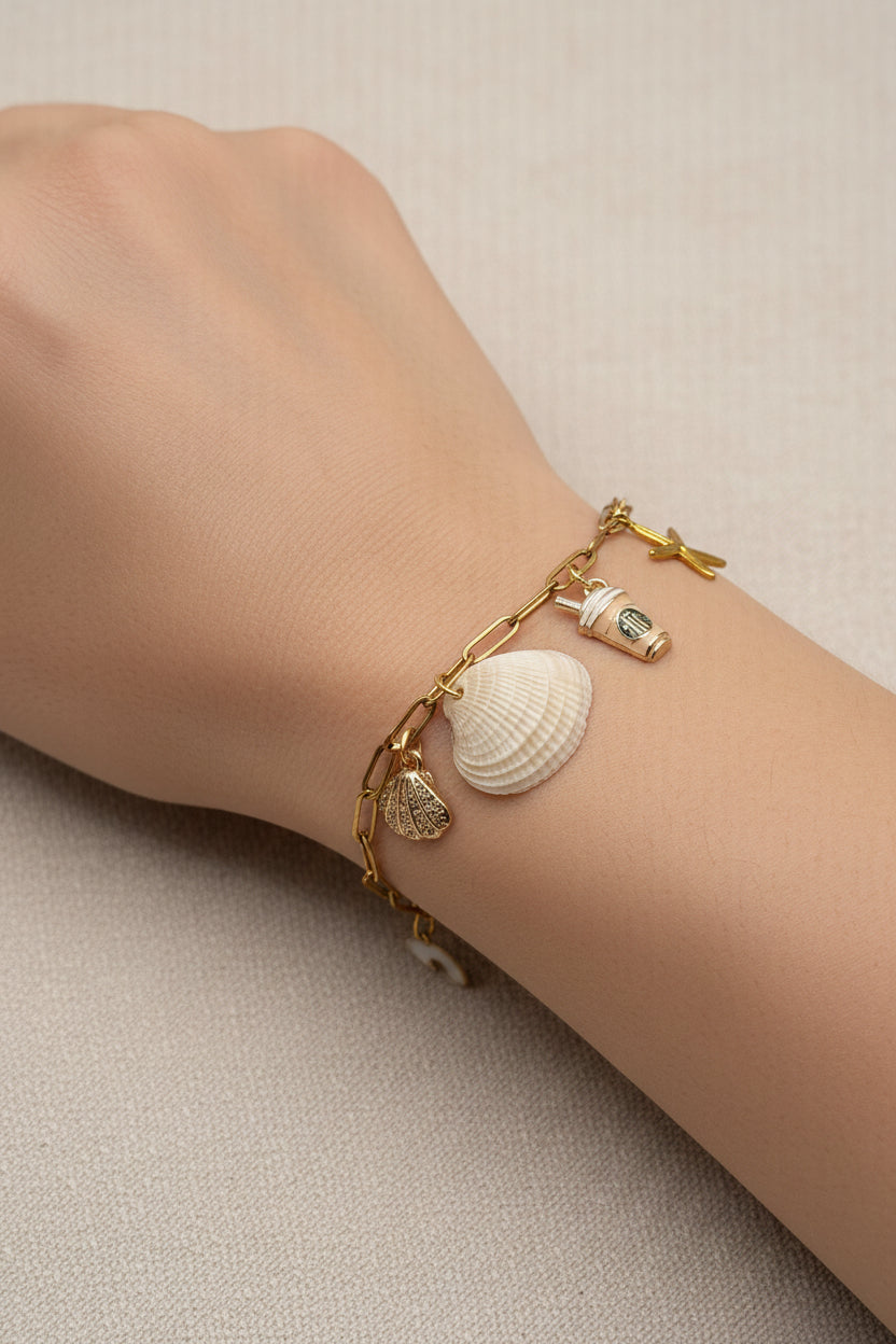 Ribbed venus clam shell charm bracelet on blue background showing starfish and coffee cup charms