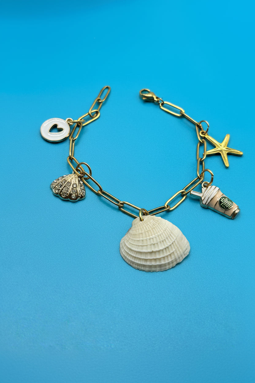 Ribbed venus clam shell charm bracelet on blue background overhead view
