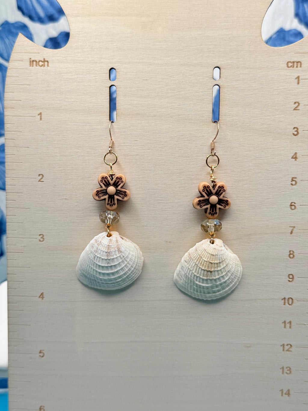 Ribbed venus clam shell earrings on white display stand showing full pair