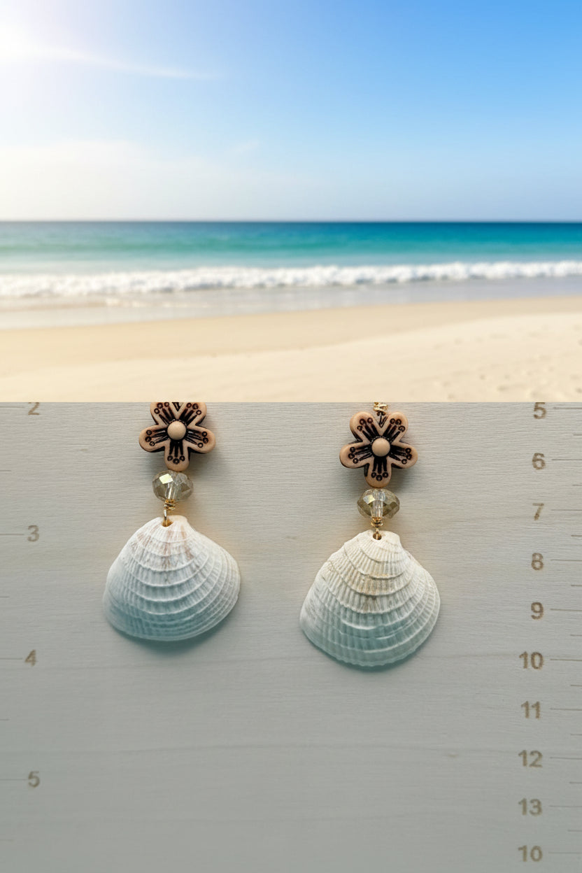 Ribbed venus clam shell earrings on display stand with blue shell backdrop