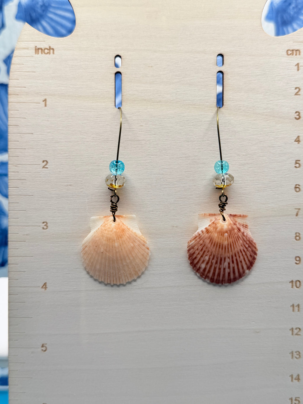 Pair of calico scallop shell earrings on ruler showing both shells and bead detail