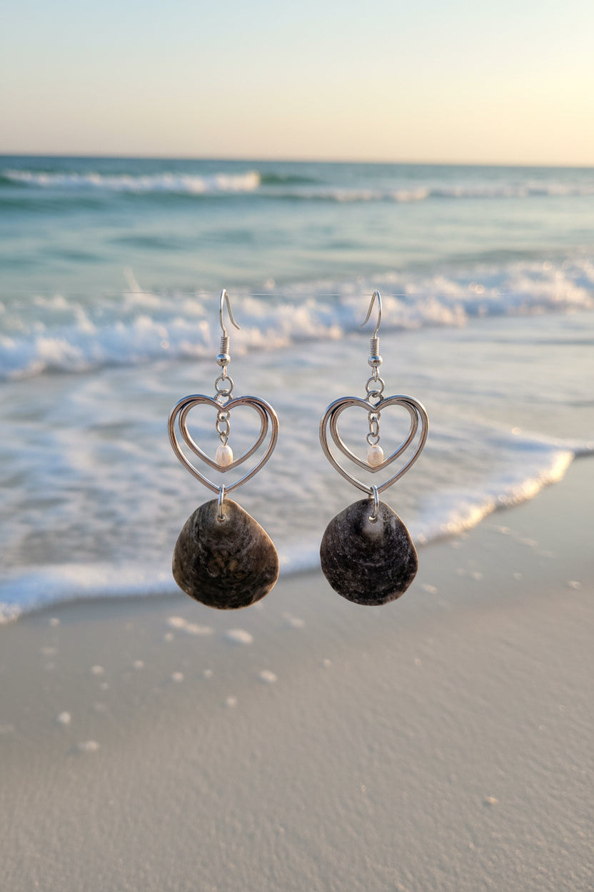 Pair of gray jingle shell double heart earrings on ruler showing full drop length front view