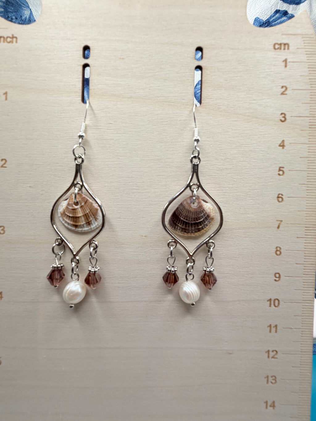 Pair of calico scallop shell chandelier earrings on ruler showing full drop