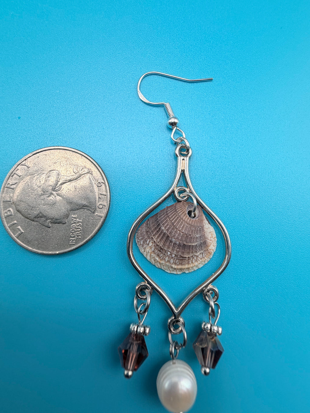 Pair of calico scallop shell chandelier earrings on ruler showing 4 inch drop side view