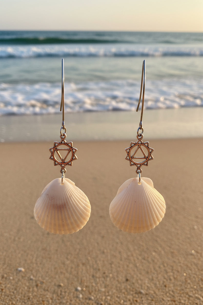 White and gray scallop shell chakra earrings on blue background with dime for scale