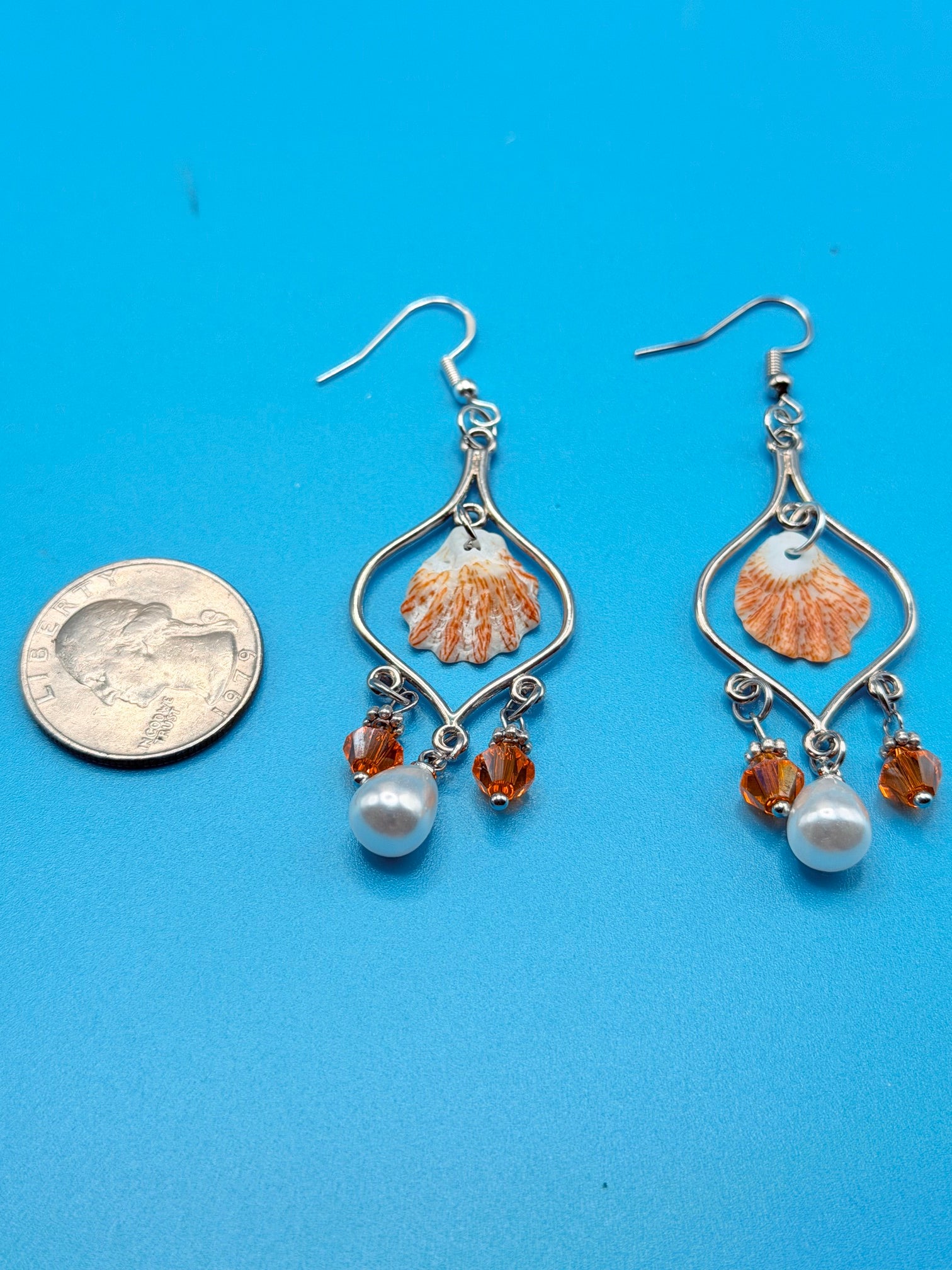 Pair of kitten paw shell chandelier earrings on ruler showing full length