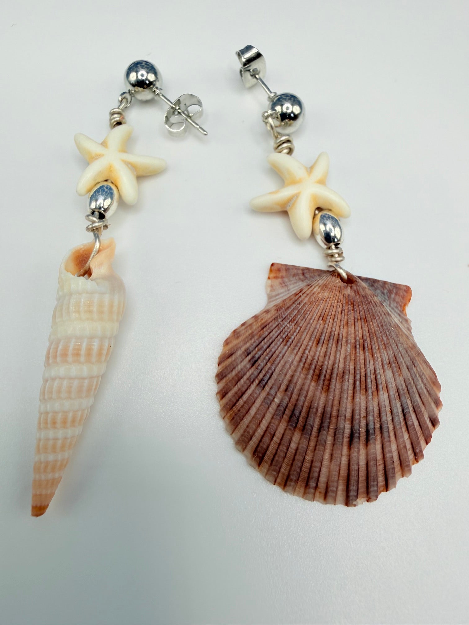 Mismatched shell earrings on white background with quarter for scale