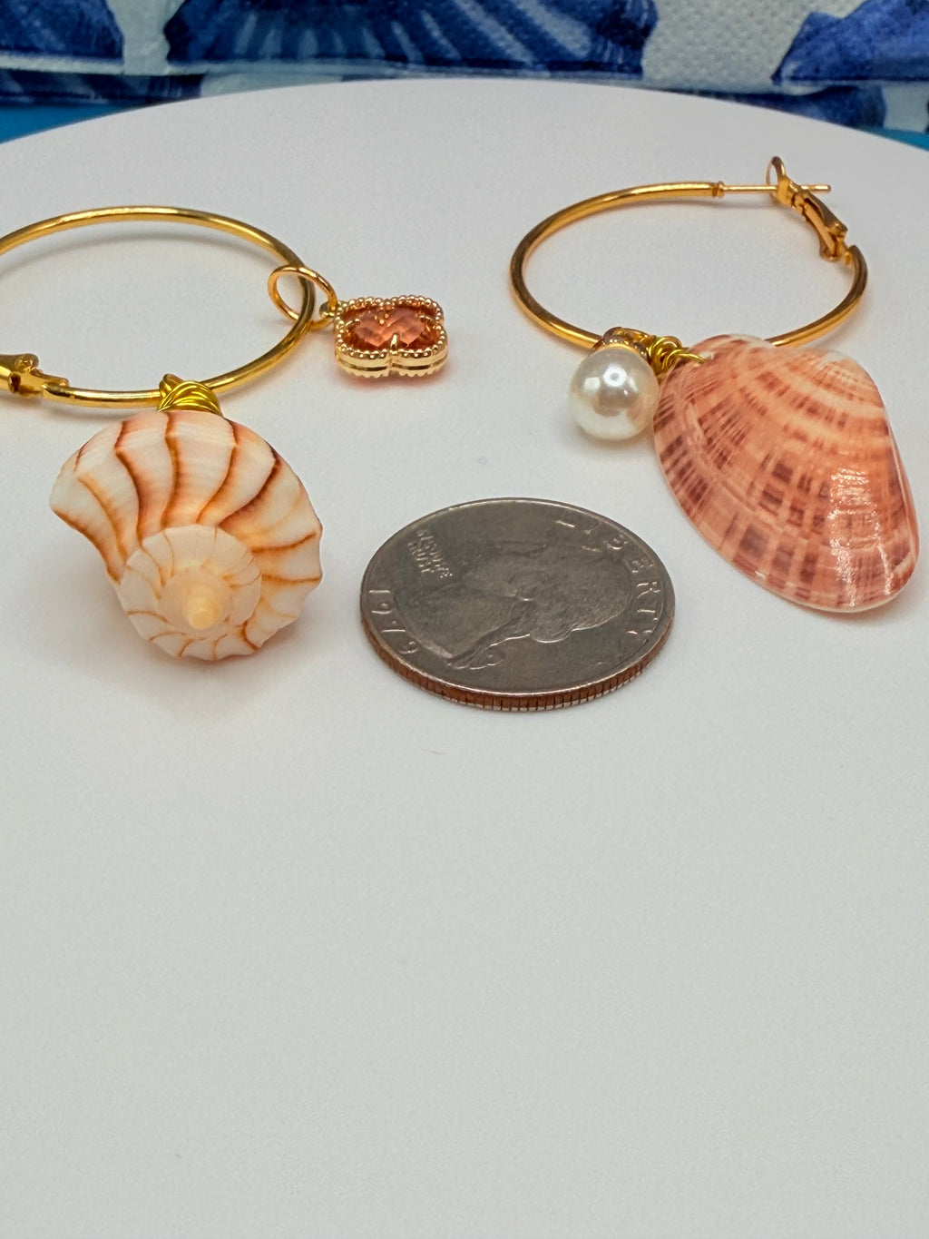 Mismatched shell hoop earrings on wood mermaid display stand showing full pair