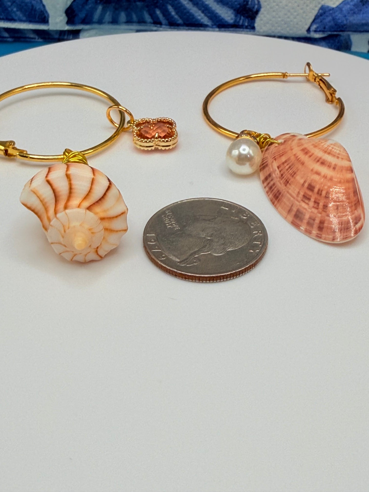 Mismatched shell hoop earrings on wood mermaid display stand showing full pair