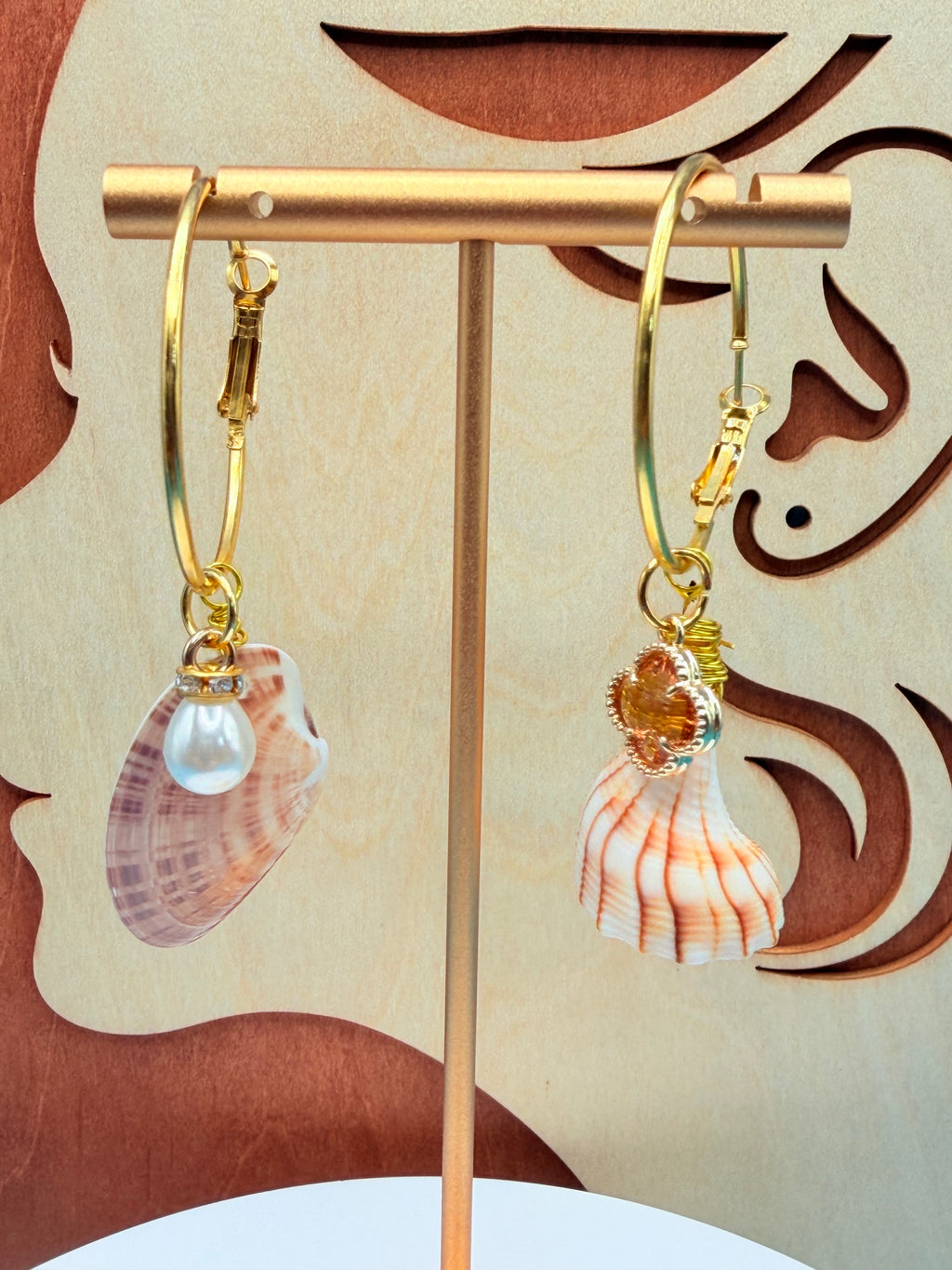 Mismatched shell hoop earrings on white surface with quarter for scale overhead view