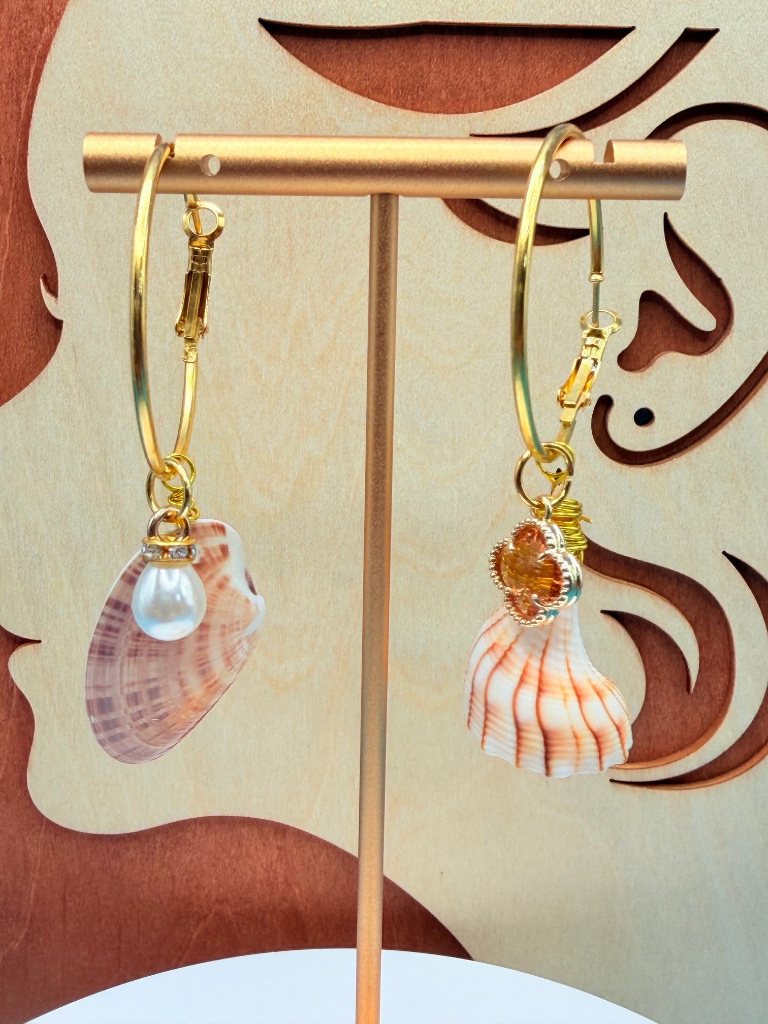 Mismatched shell hoop earrings on white surface with quarter for scale overhead view