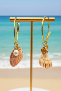 Mismatched shell hoop earrings on display stand with scallop shell backdrop close-up