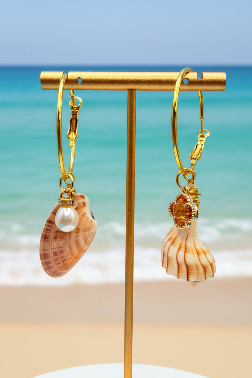 Mismatched shell hoop earrings on display stand with scallop shell backdrop close-up