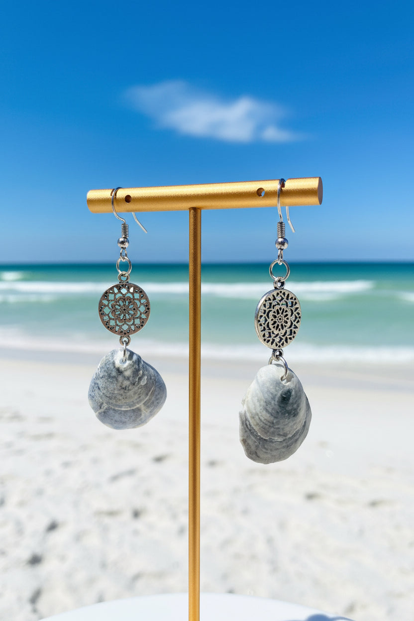 Pair of jingle shell earrings with silver filigree mandala charm next to quarter for size reference