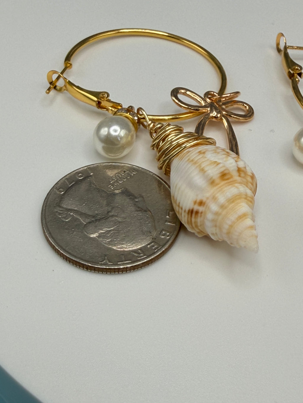 Juvenile conch shell hoop earrings flat lay on white surface