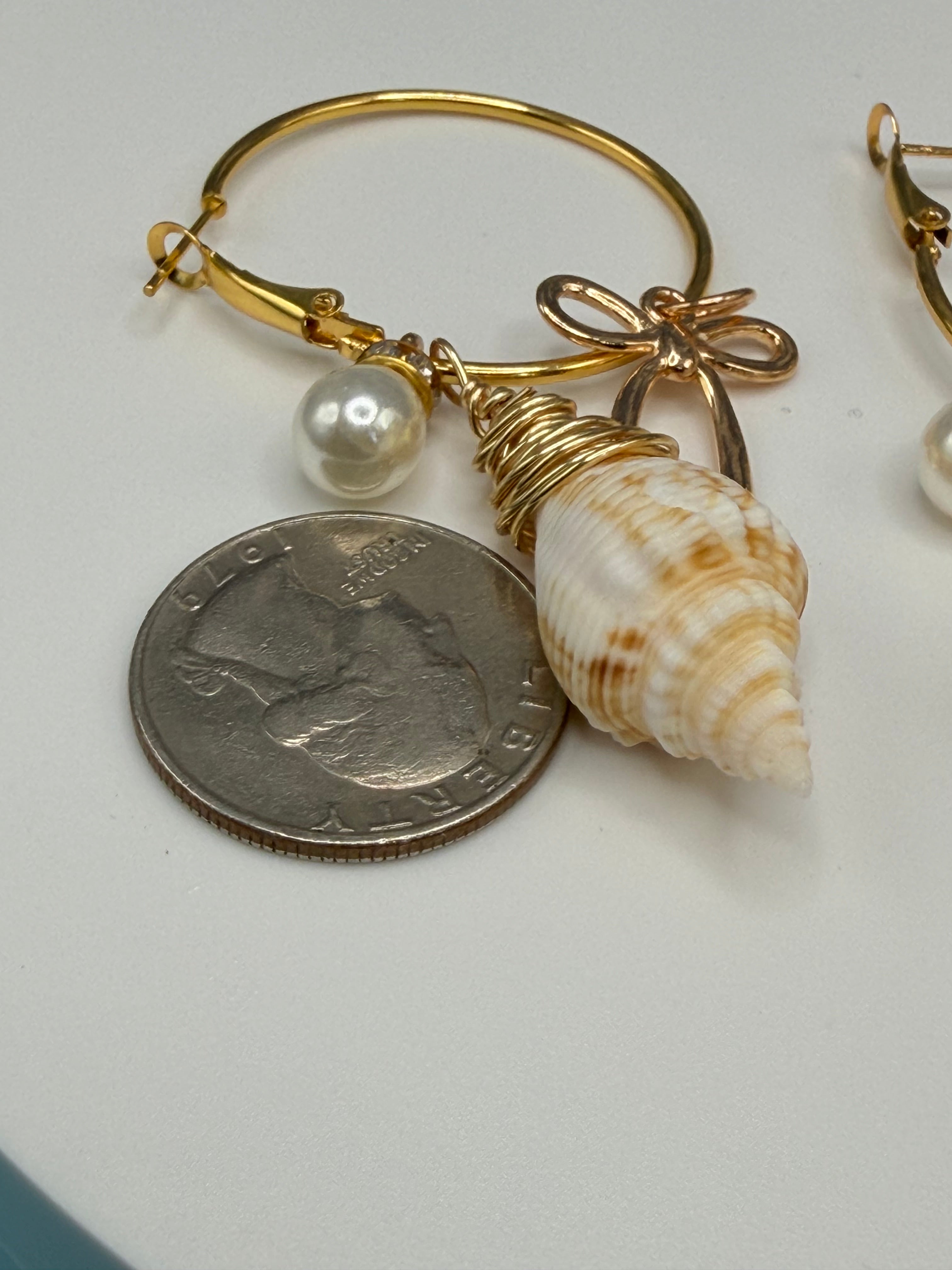 Juvenile conch shell hoop earrings flat lay on white surface