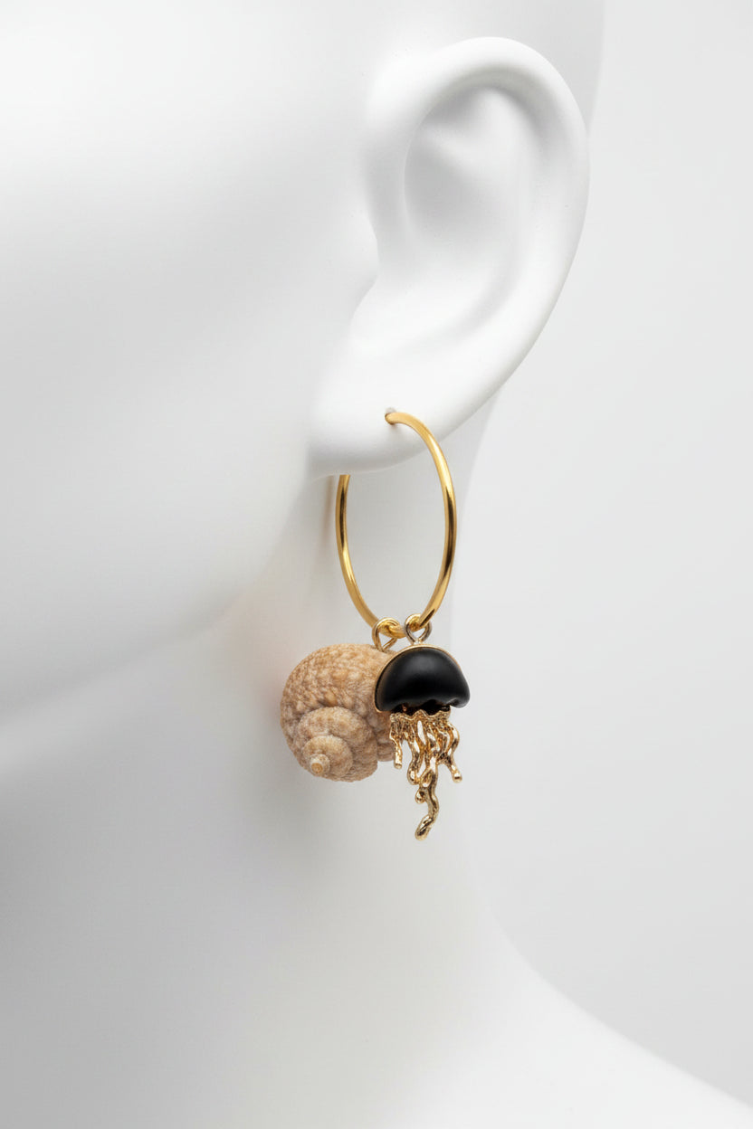 Turban shell hoop earrings with jellyfish charm on gold display stand against blue shell background